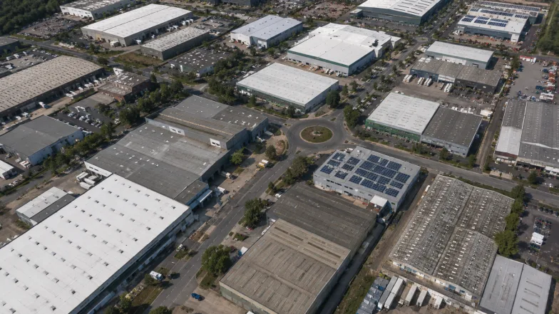 Aerial view across an industrial estate of many roofs of differing age, condition and solar coverage